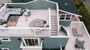 A two-story house with a covered patio area featuring a sofa set, a circular seating area, and a dining table with chairs. - This home is close to the train, the beach and all the amazing downtown restaurants! (Oceanside)