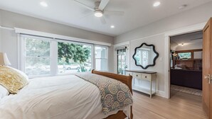 A bedroom with a bed, a desk, a mirror, and a wardrobe.