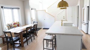 A modern kitchen with a central island, white cabinetry, and a gold pendant light.
