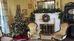 A traditional living room with a fireplace, a Christmas tree, and two armchairs. - Historic Home - Victorian Stage Coach Inn (Russellville)
