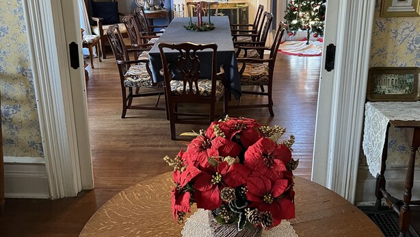 A dining room with a round table, chairs, a chandelier, and a Christmas tree. - Historic Home - Victorian Stage Coach Inn (Russellville)