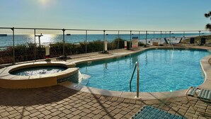 A swimming pool with a hot tub, lounge chairs, and a view of the ocean.