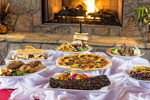 Un tavolo da buffet con diversi piatti di fronte a un camino in pietra.