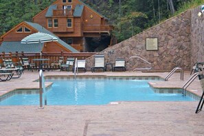 Area piscina con lettini e una cabina di legno sullo sfondo.