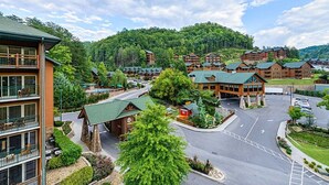 Eine Lodge mit mehreren Holzhütten, einem zentralen Gebäude und einem Parkplatz, umgeben von viel Grün.