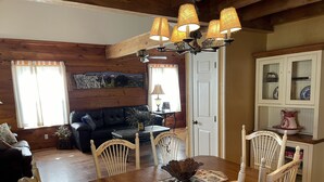 A cozy cabin interior with a wooden dining table, white chairs, a black leather sofa, and a painting on the wall. - Weekend hiking trips at Fall Creek Falls & surrounding State Parks. (Spencer)