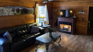 A cabin interior with a leather sofa, a table, a fireplace, and a ceiling fan. - Weekend hiking trips at Fall Creek Falls & surrounding State Parks. (Spencer)