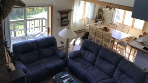 Ett vardagsrum med två mörkblå soffor, ett matbord i trä med stolar, en lampa och en staty av en man.
