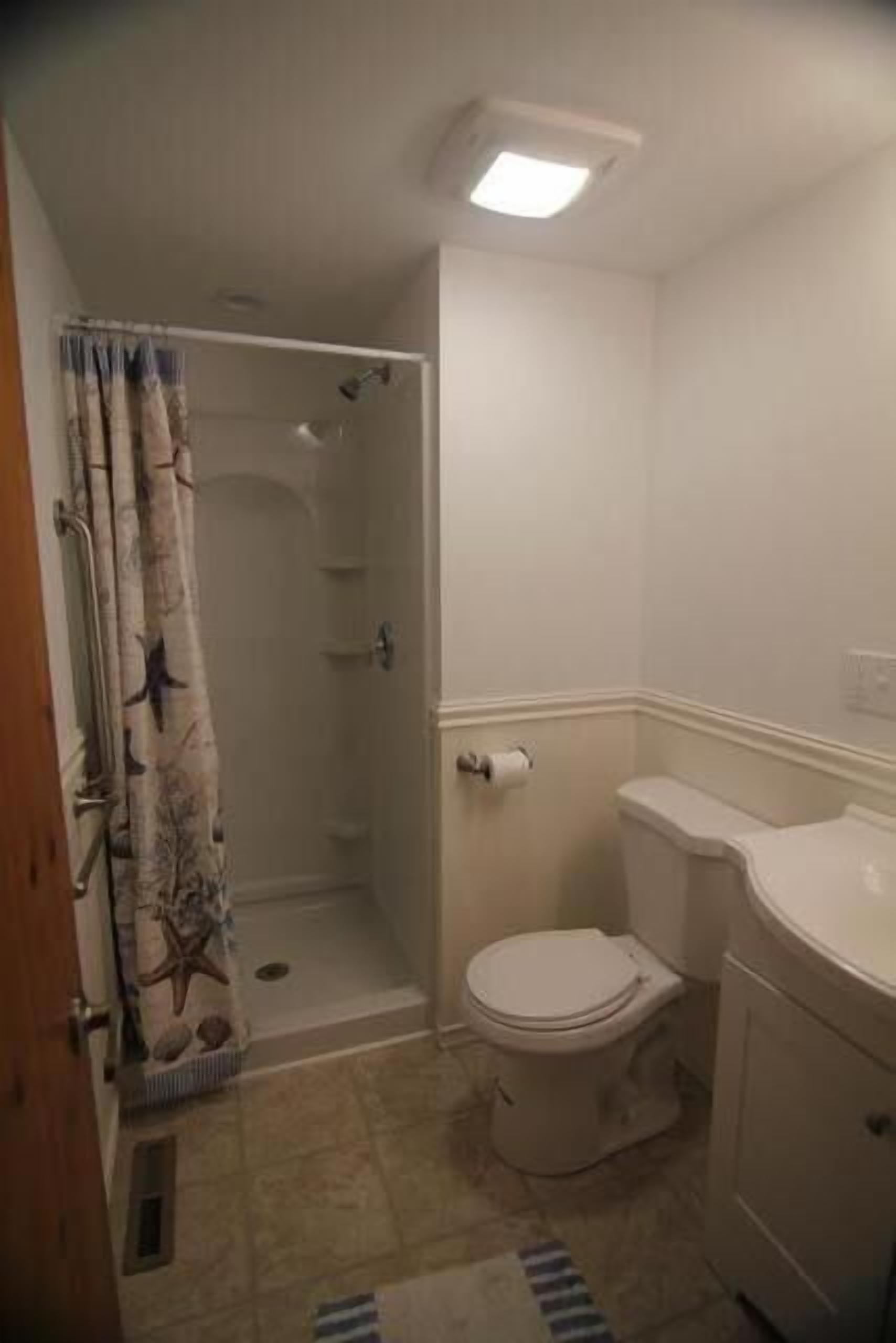 Un baño pequeño con ducha, inodoro y lavamanos.