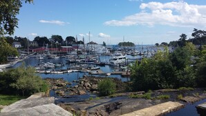 Un port de plaisance où sont amarrés des bateaux, entouré de verdure et de bâtiments.