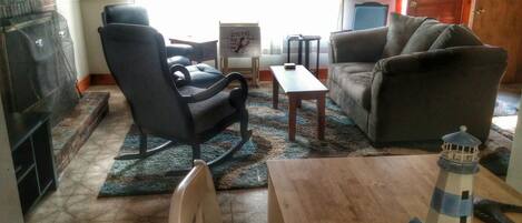 A living room with a fireplace, a sofa, a rocking chair, a small table, and a decorative lighthouse model.