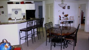 A dining area with a wooden table and chairs, a kitchen area with white cabinets, and a globe on a stand. - Modern 2000 sqft Condo with a Million Dollar Unobstructed Full Main Channel View (Lake Ozark)