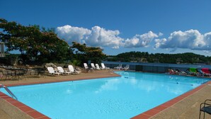 A swimming pool with lounge chairs and a view of a lake. - Modern 2000 sqft Condo with a Million Dollar Unobstructed Full Main Channel View (Lake Ozark)