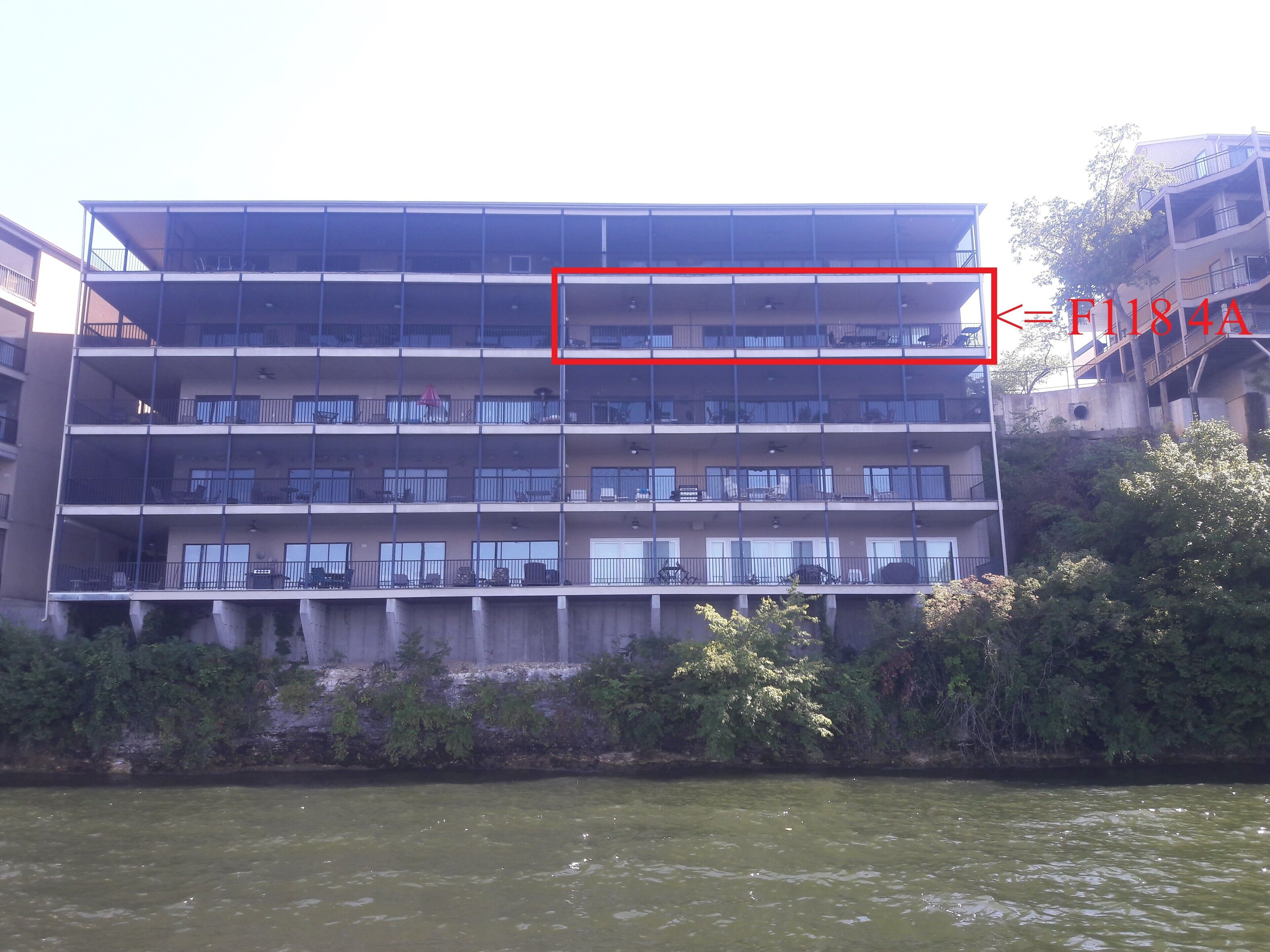 Un edificio de varios pisos con balcones, cerca de una masa de agua.