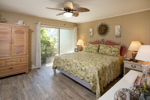 A bedroom with a bed, a ceiling fan, a nightstand, a lamp, and a wardrobe. - SeaPines, Beautifully updated, Walk to beach, Two free bikes, Pet friendly (hilton head)