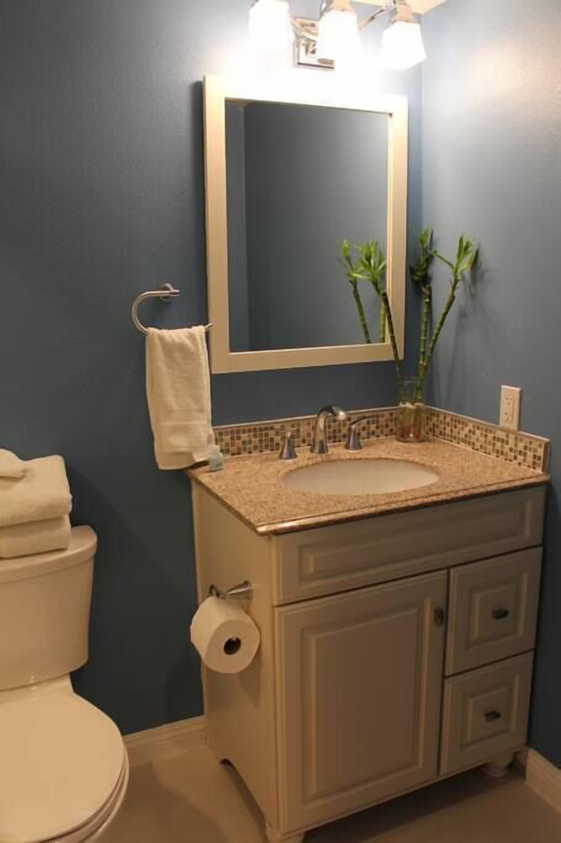 Un baño con lavamanos blanco, un espejo, toallero y un inodoro.