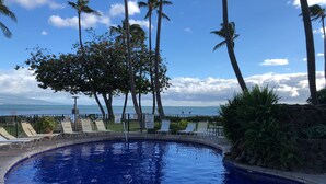 A swimming pool with lounge chairs and a view of the ocean. -  Crew Rest Maui - 2BR/2BA, Oceanfront, Superior Views, A/C, sleeps 6 (Wailuku)