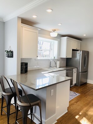 A modern kitchen with a central island, stainless steel appliances, and a window providing natural light.