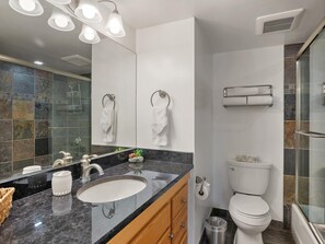 Ein modernes Badezimmer mit großem Spiegel, Waschbecken, Toilette und Duschbereich.
