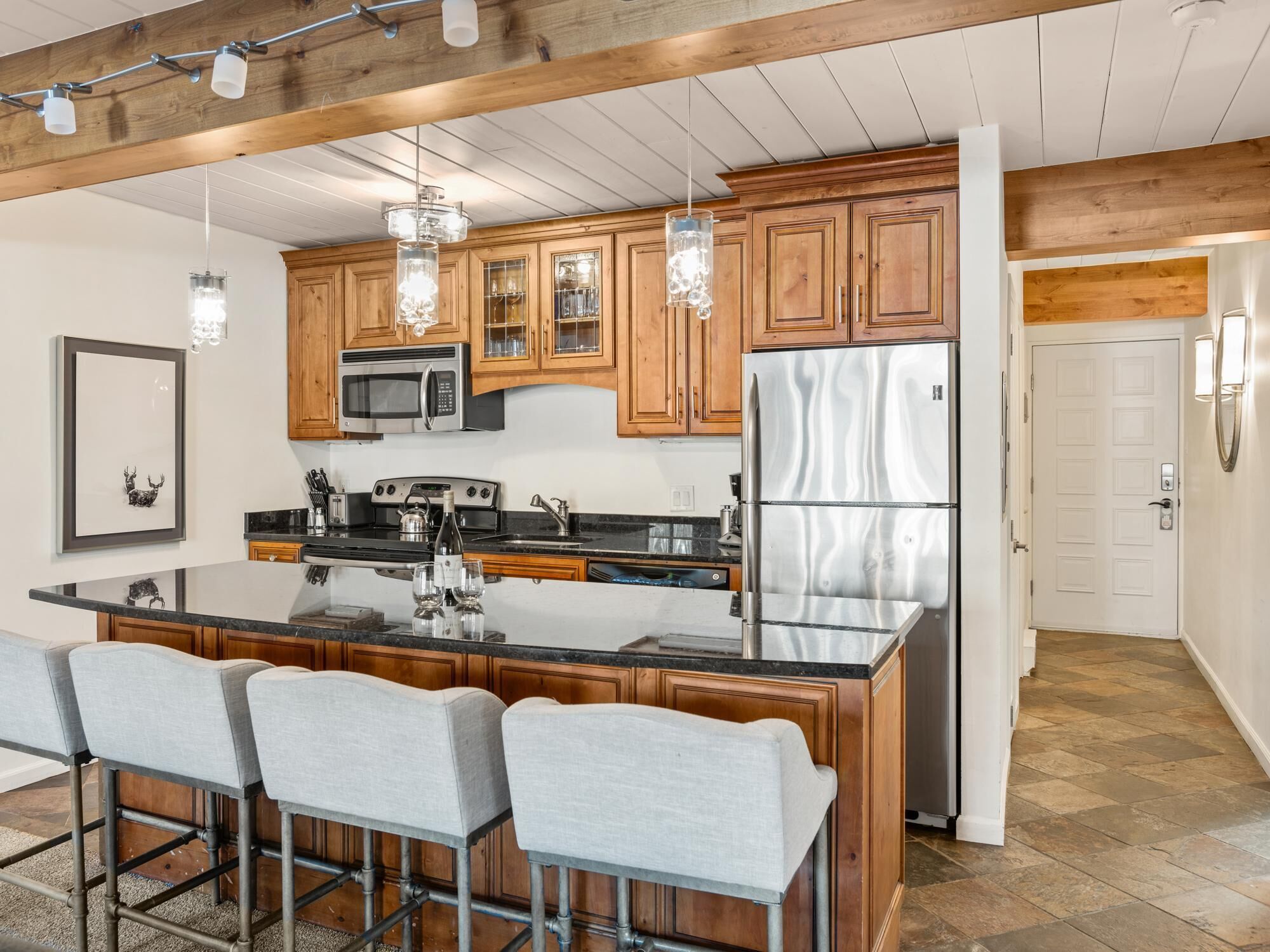 A modern kitchen with wooden cabinets, stainless steel appliances, and a central island with bar stools.