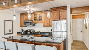Una cocina moderna con armarios de madera, electrodomésticos de acero inoxidable y una isla central con taburetes de bar.