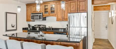 A modern kitchen with wooden cabinets, stainless steel appliances, and a central island with bar stools.
