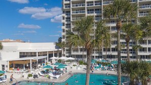 Um hotel com uma grande piscina ao ar livre rodeada por palmeiras e espreguiçadeiras.