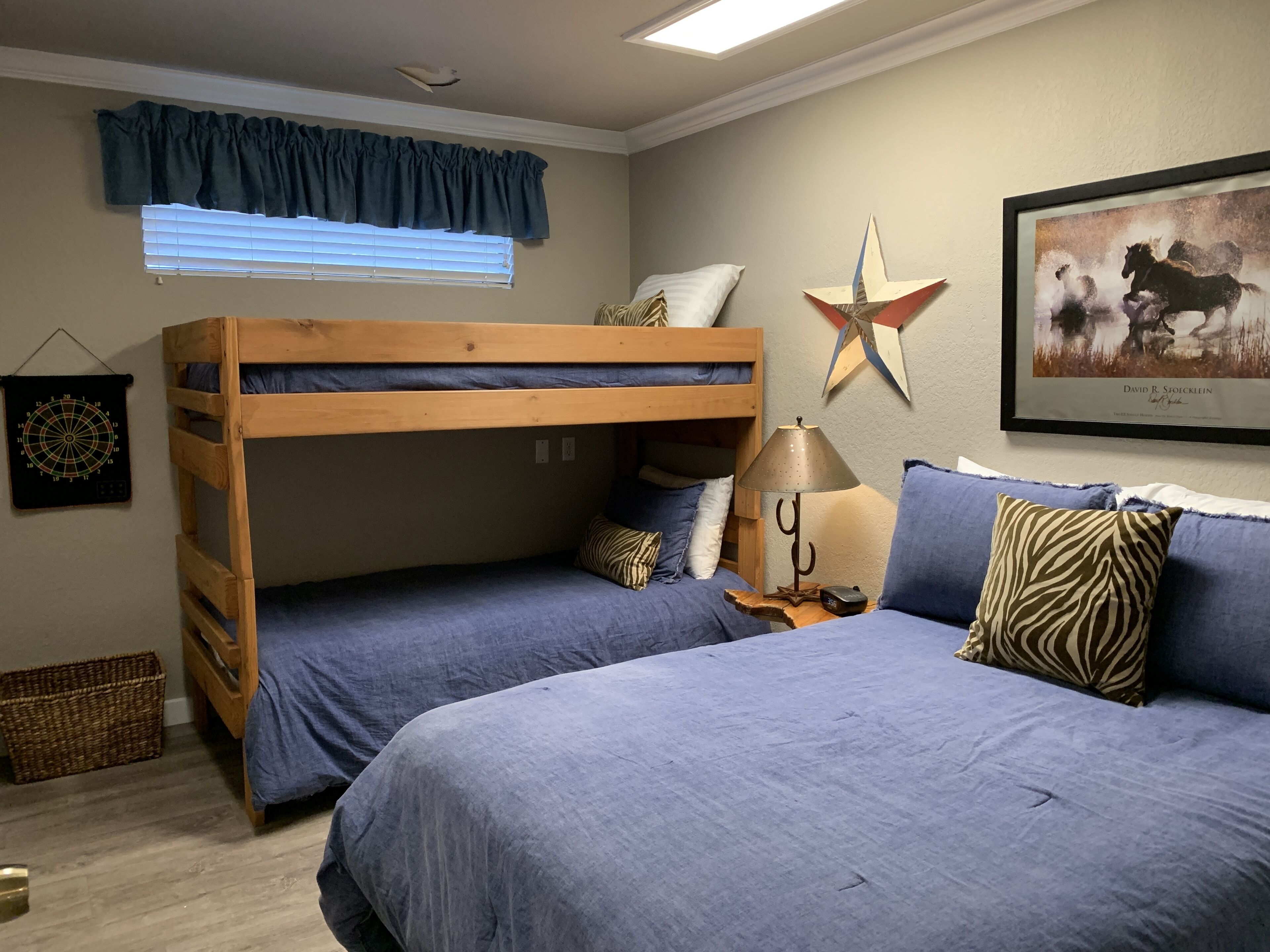 Une chambre avec un lit superposé décoré de motifs d’étoiles, un tableau encadré et une lampe.