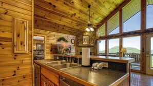 A wooden cabin interior with a kitchen area, large windows, and a view of the outdoors. - 4 bedroom 4 bathroom sleeps 14 outdoor pool access great mountain views and free internet access (Sevierville)