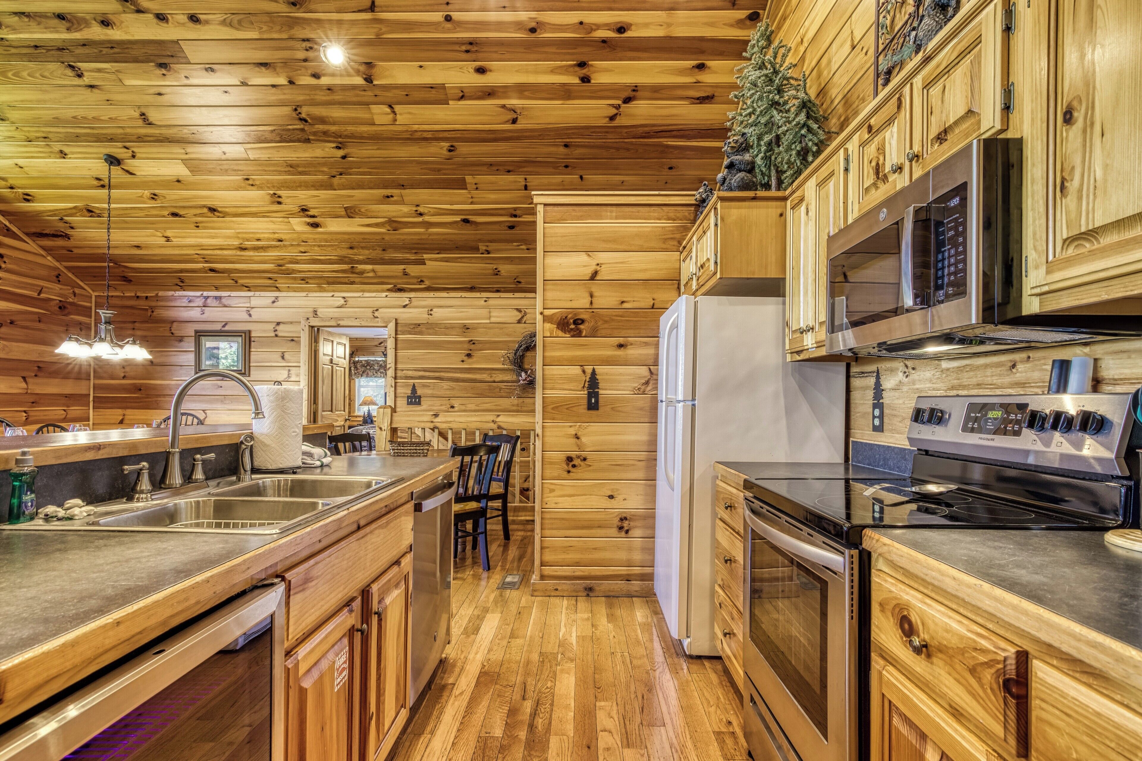 A wooden cabin-style kitchen with a wooden ceiling, stainless steel appliances, and a built-in microwave.