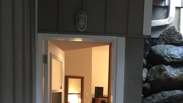 A doorway leading to a room with a mirror, a lamp, and a wooden cabinet. - Cute and  Cozy basement unit in Tremblant (Mont-Tremblant)