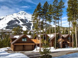 A lodge with multiple cabins, a mountain backdrop, and a clear sky.