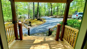 A wooden deck leading to a forested area with a gravel path and a white car parked nearby. - The Mountains are calling for You and Yours!
      (Cleveland)