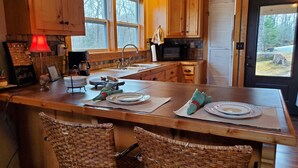 A kitchen with wooden cabinets, a large island with chairs, a microwave, and a sink. - The Mountains are calling for You and Yours!
      (Cleveland)