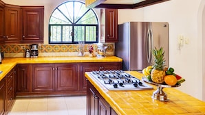 A kitchen with wooden cabinets, a gas stove, a stainless steel refrigerator, and a window with a view of greenery. - French-Colonial Villa,Close to Paseo Montejo, Hotels and Restaurants! (Mérida)