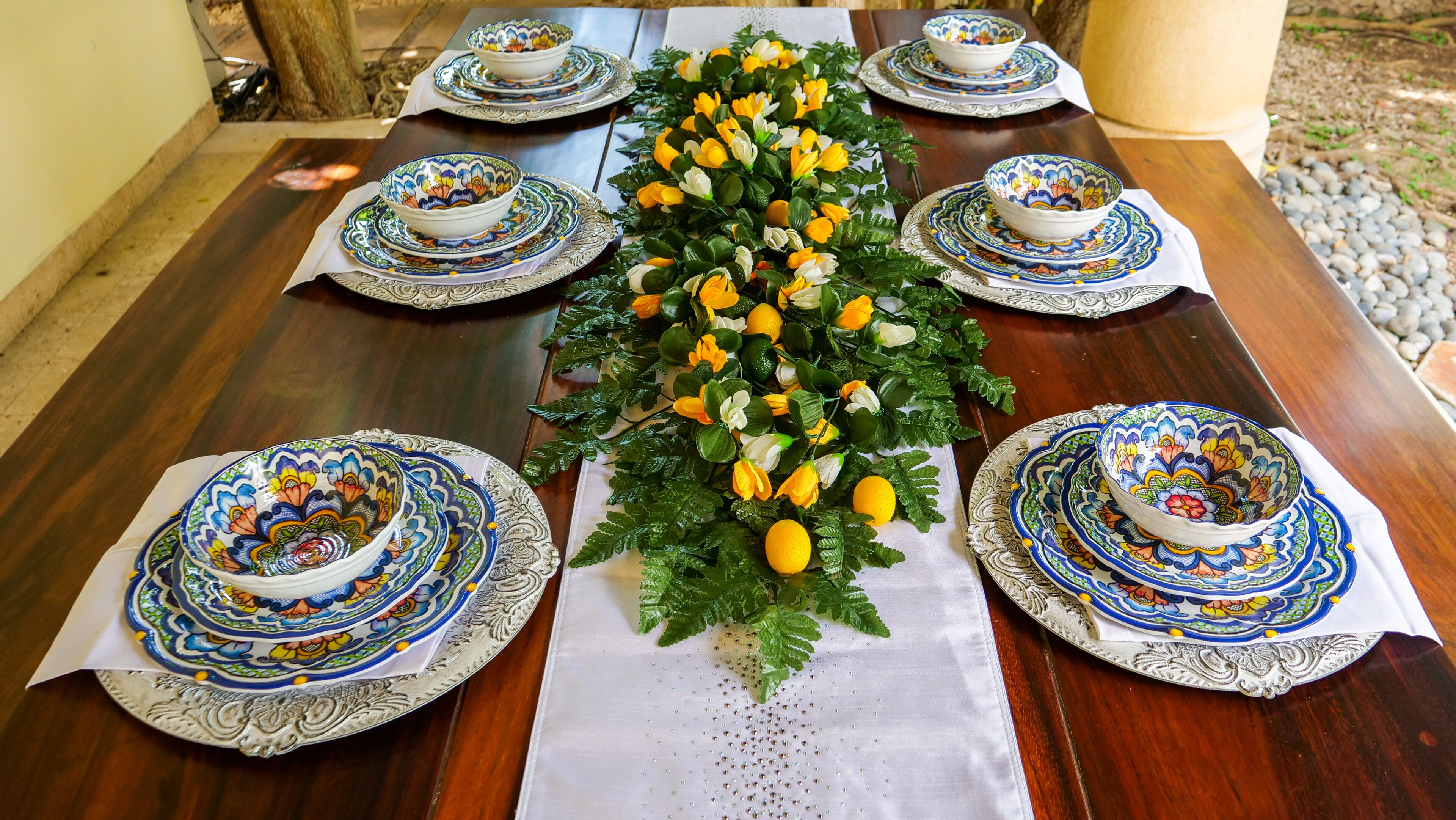 A dining table set with ornate bowls and plates, surrounded by a decorative floral arrangement.