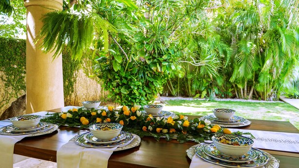 An outdoor dining area with a table set for a meal, surrounded by lush greenery and a stone pillar. - French-Colonial Villa,Close to Paseo Montejo, Hotels and Restaurants! (Mérida)