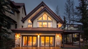 A modern house with a large front porch, stone accents, and a balcony.