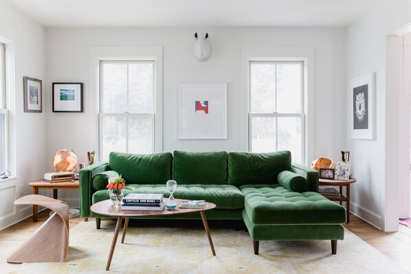 Ein modernes Wohnzimmer mit einem grünen, modularen Sofa, einem Holztisch und einer globoartigen Stehlampe.