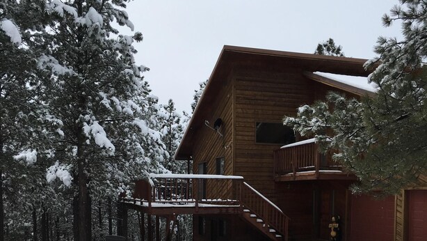 A wooden cabin with a porch and a snowman. - Walk To Slopes & Restaurants! (Angel Fire)
