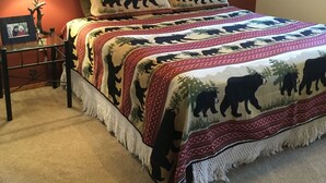 A bedroom with a bed, a nightstand, a lamp, a cross on the wall, and a window. - Walk To Slopes & Restaurants! (Angel Fire)