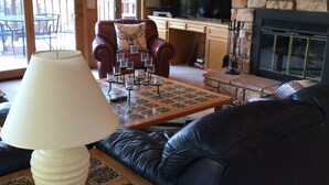 A cozy living room with a fireplace, leather sofas, a coffee table, and a television. - Walk To Slopes & Restaurants! (Angel Fire)