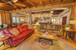 A spacious living room with leather sofas, a wooden coffee table, and a large rug. - WOW Huge Catfish Lake Home 13br 5ba, Sleeps 26, Eag River Chain/weddings/events (Eagle River)