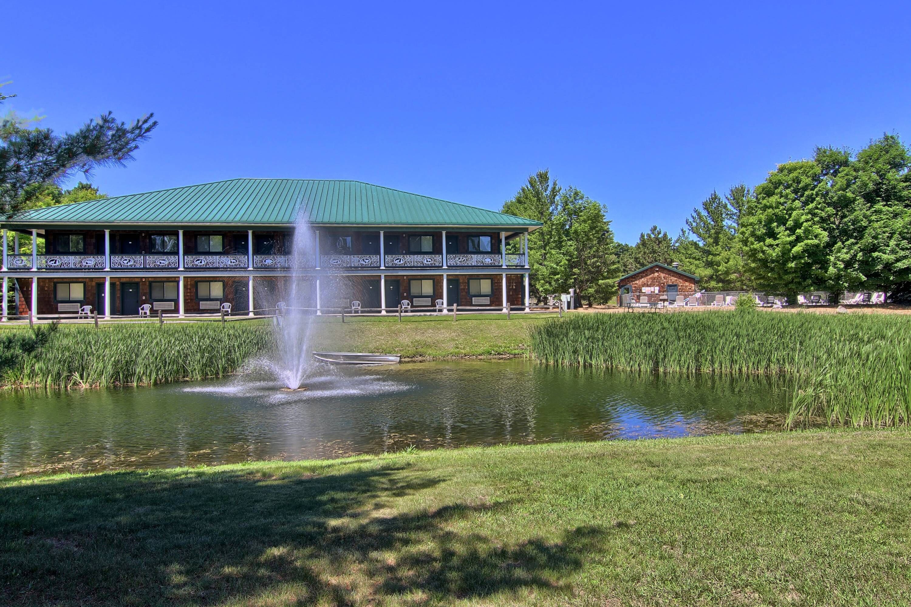 A building with a green roof, a fountain in front, and a pond.