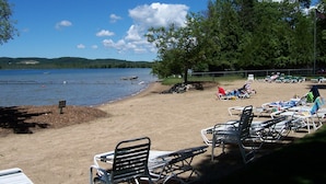 Una playa con sillones de descanso y vista al lago.