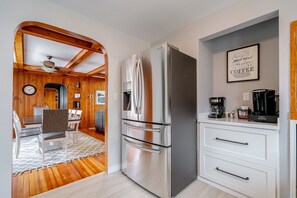 A modern kitchen with a stainless steel refrigerator, white cabinetry, and a coffee maker on the counter.