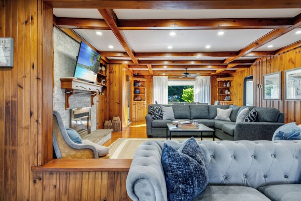 A cozy living room with a fireplace, a large sofa, and a television. - Sunsets by the Bay - Your Waterfront Oasis (Leamington)