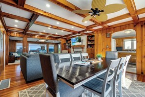 A spacious dining area with a large table and multiple chairs, a ceiling fan, and wooden beams. - Sunsets by the Bay - Your Waterfront Oasis (Leamington)