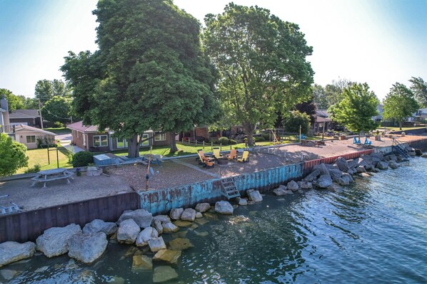 Un parque frente al agua con mesas de picnic, bancos y un parque infantil.
