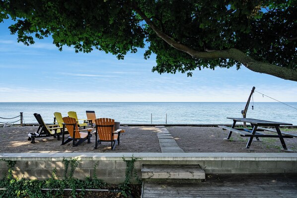 A beachside seating area with Adirondack chairs and a picnic table, overlooking the sea.